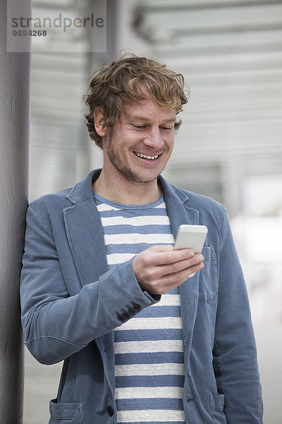 Porträt eines lächelnden Mannes mit Smartphone Lesung SMS