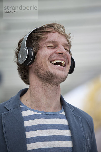 Porträt eines glücklichen Mannes mit Kopfhörer  der Musik hört
