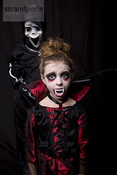 Mädchenmaske als Vampir und Junge mit Scream-Maske