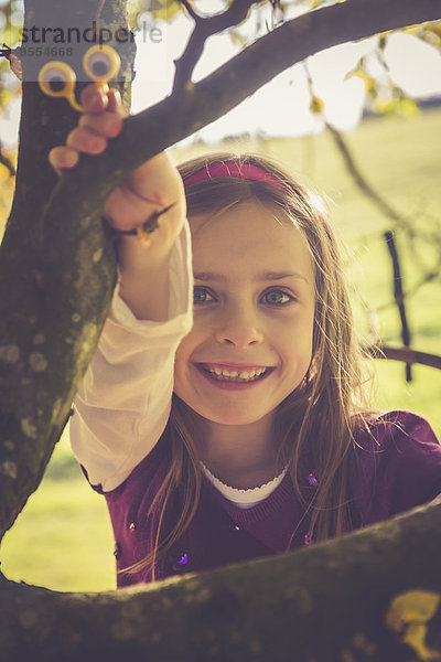 Porträt eines lächelnden kleinen Mädchens beim Klettern in einem Baum