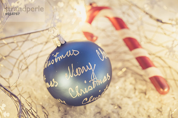 Blaue Weihnachtskugel mit den Worten'Frohe Weihnachten' und rot-weißem Zuckerrohr