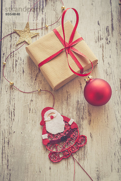 Weihnachtsgeschenk mit roter Weihnachtskugel und Weihnachtsmann auf Holz