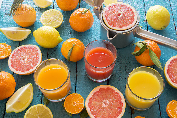 Gläser Orangensaft  Grapefruitsaft und Multivitaminsaft  Saftpresse und Früchte auf Holz