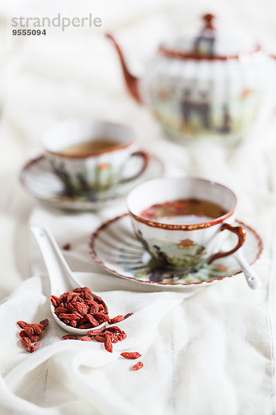 Tasse grüner Tee mit getrockneten Goji-Beeren  Lycium barbarum