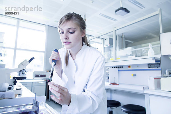 Junge Naturwissenschaftlerin beim Färben eines Objektträgers für das Lichtmikroskop im Mikrobiologie-Labor