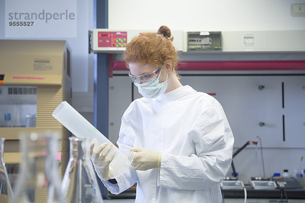 Junge Naturwissenschaftlerin mit Maske im Labor für Biochemie