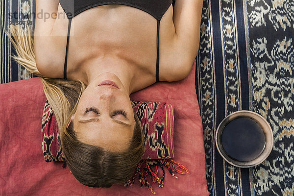 Frau auf der Decke liegend meditierend