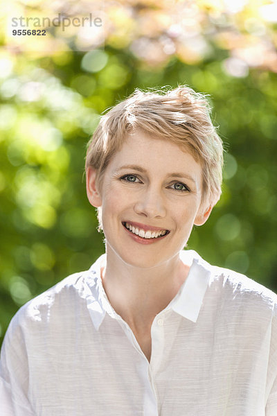 Porträt einer lächelnden Frau mit kurzen blonden Haaren