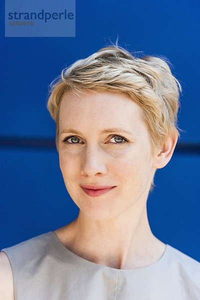 Porträt einer blonden Frau vor blauem Hintergrund