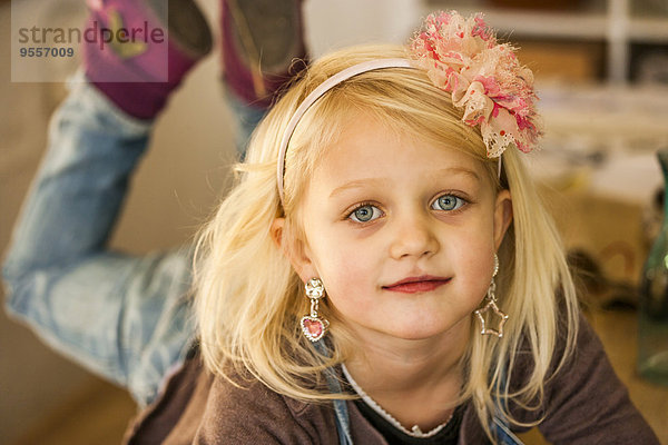 Porträt eines blonden Mädchens mit Ohrringen und Haarband