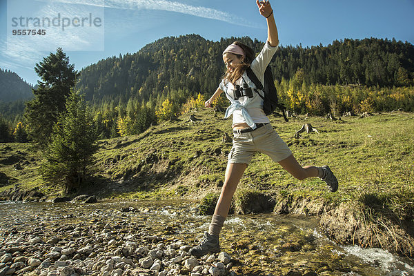Österreich  Tirol  Tannheimer Tal  junge Wanderin beim Überqueren des Wassers
