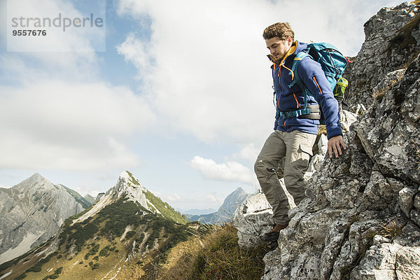 Österreich  Tirol  Tannheimer Tal  junger Mann beim Wandern auf Felsen