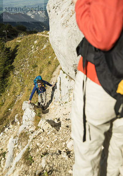 Österreich  Tirol  Tannheimer Tal  junges Paar beim Wandern auf Felsen