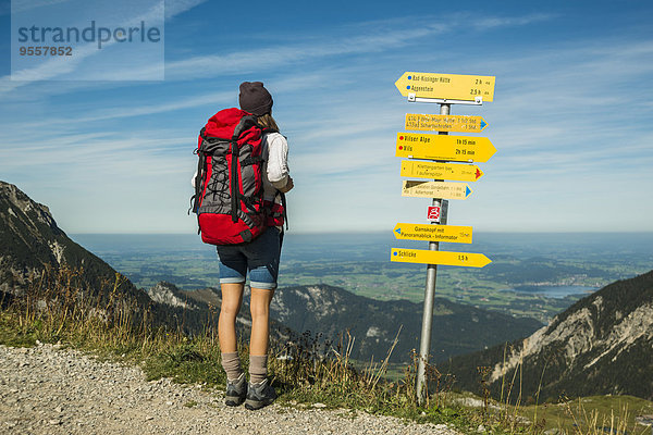 Österreich  Tirol  Tannheimer Tal  junge Frau auf Wanderung am Wegweiser