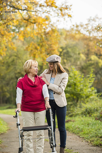 Seniorin und ihre erwachsene Enkelin beim gemeinsamen Spaziergang im Herbstpark