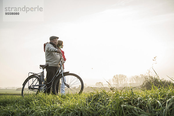 Senior Mann und Tochter in ländlicher Landschaft mit Fahrrad
