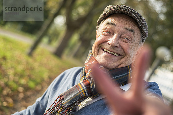 Porträt eines glücklichen älteren Mannes im Freien mit Siegeszeichen