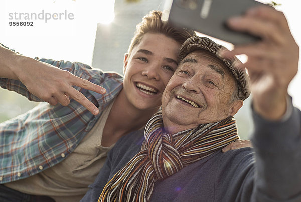 Glücklicher älterer Mann  der einen Selfie mit Enkel nimmt.