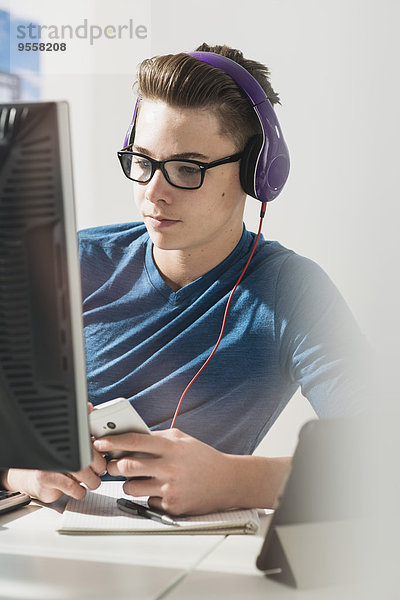 Junger Mann am Schreibtisch mit Kopfhörer