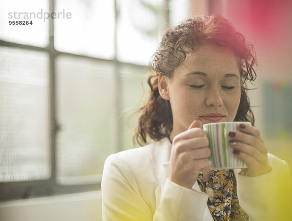Junge Geschäftsfrau genießt eine Tasse Kaffee