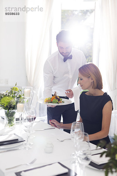 Kellner serviert Abendessen für die Frau in einem eleganten Restaurant.