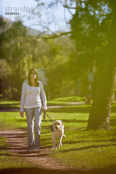 Sehbehinderte Frau beim Spaziergang mit Blindenhund im Park
