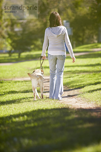 Sehbehinderte Frau beim Spaziergang mit Blindenhund im Park