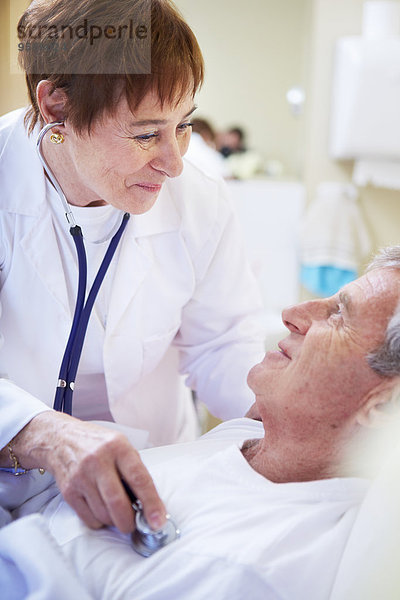 Arzt untersucht älteren Mann im Krankenhausbett