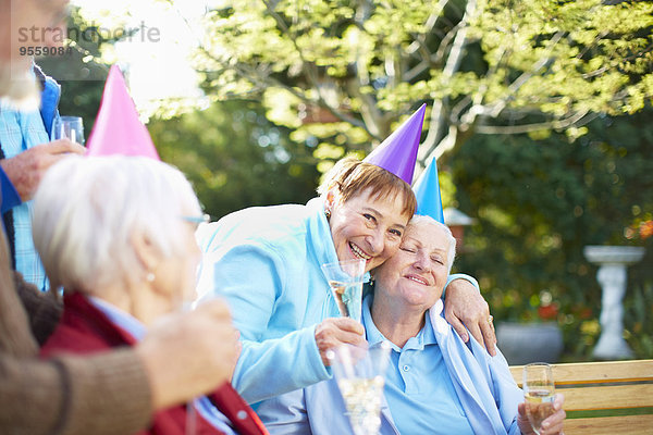 Seniorenfreunde beim Umarmen auf einer Geburtstagsgartenparty
