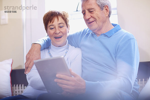 Glückliches Seniorenpaar mit digitalem Tablett zu Hause