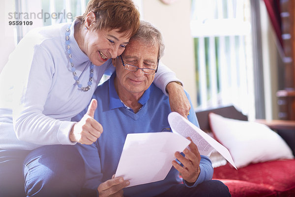 Glückliches Seniorenpaar liest Dokument zu Hause