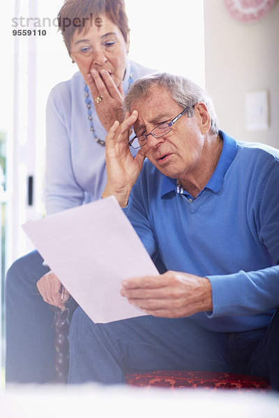 Schockiertes Seniorenpaar beim Lesen des Dokuments zu Hause