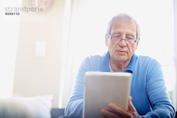 Senior Mann mit digitalem Tablett zu Hause