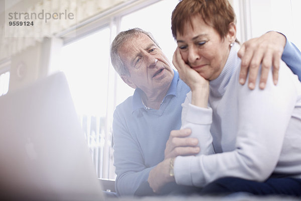 Senior Mann tröstet weinende Frau am Laptop