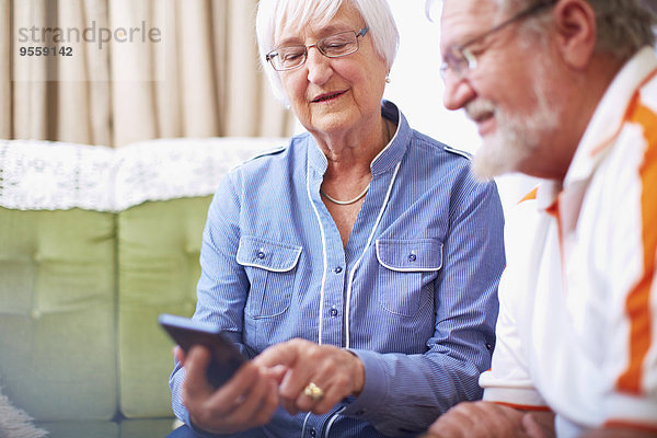 Seniorenpaar mit Smartphone zu Hause