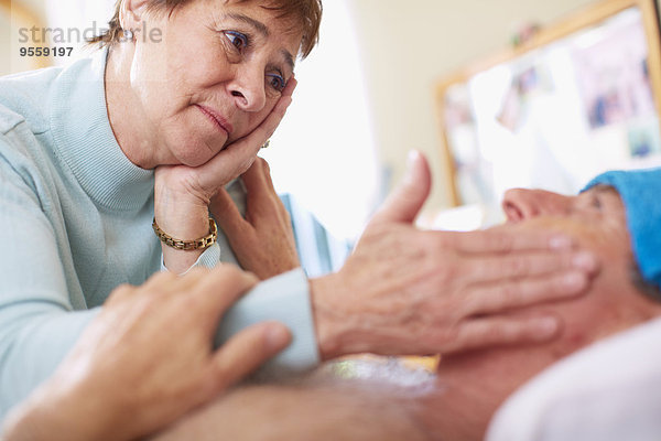 Seniorin  die sich zu Hause um ihren kranken Mann kümmert.