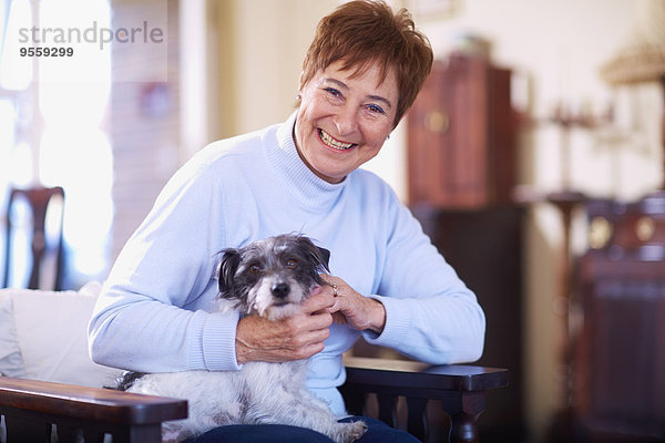 Glückliche Seniorin mit Hund zu Hause