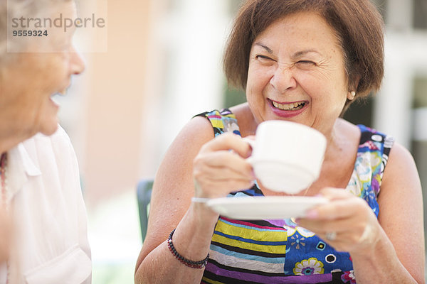 Zwei glückliche Seniorinnen  die zusammen Kaffee trinken.