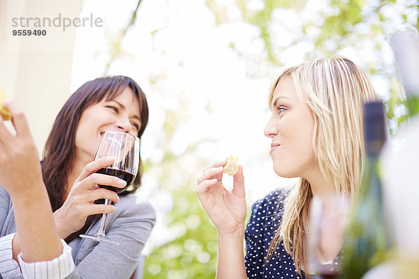 Zwei glückliche Frauen mit Rotwein und Weißbrot