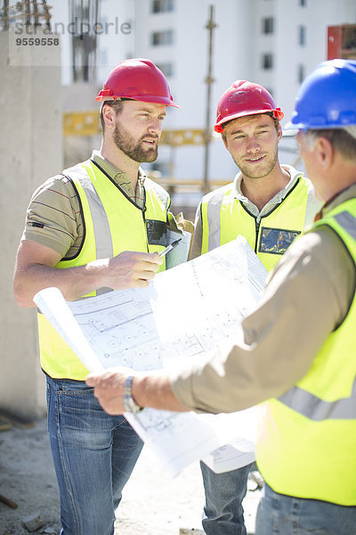Bauarbeiter diskutieren Baupläne auf der Baustelle