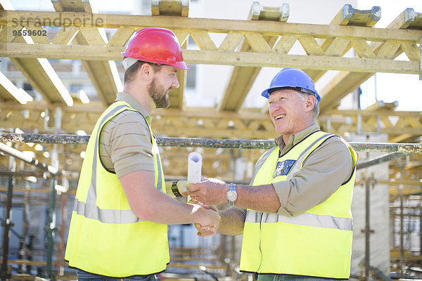 Zwei Bauarbeiter beim Händeschütteln auf der Baustelle