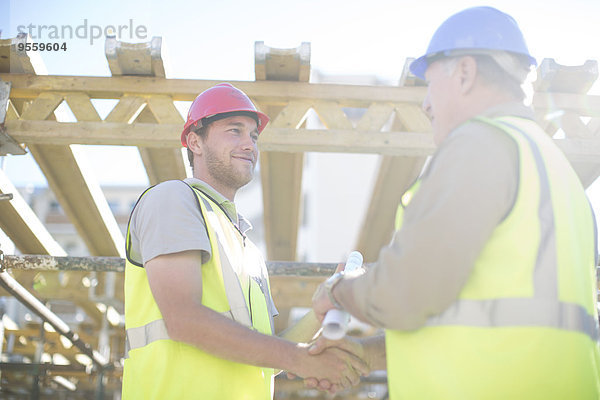 Zwei Bauarbeiter beim Händeschütteln auf der Baustelle