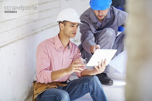Bauarbeiter und Vorarbeiter beim Betrachten des digitalen Tabletts