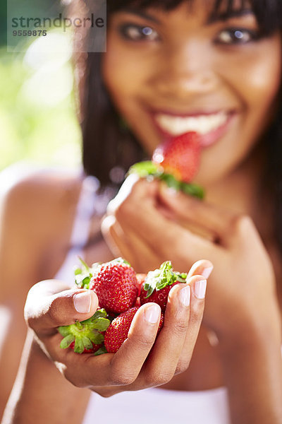 Hand einer lächelnden Frau  die Erdbeeren hält.