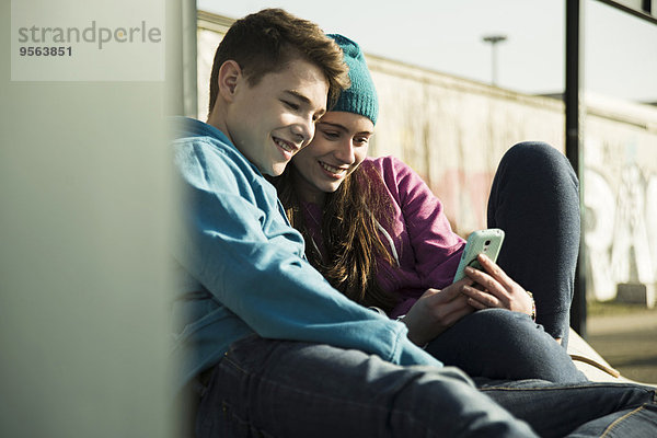 Handy sitzend Zusammenhalt Jugendlicher sehen lächeln Junge - Person Boden Fußboden Fußböden Mädchen