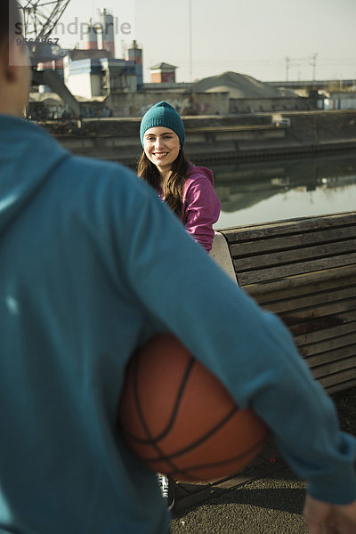 Außenaufnahme Jugendlicher sehen lächeln Junge - Person halten Basketball Kleidung Mütze Mädchen Industriegebiet freie Natur