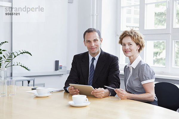 Ein Geschäftsmann und eine Geschäftsfrau  die ein digitales Tablett in einer Besprechung verwenden.