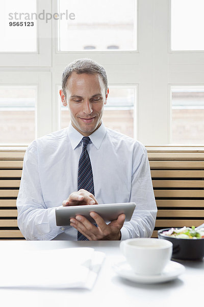 Ein Geschäftsmann  der in seiner Mittagspause ein digitales Tablett benutzt.