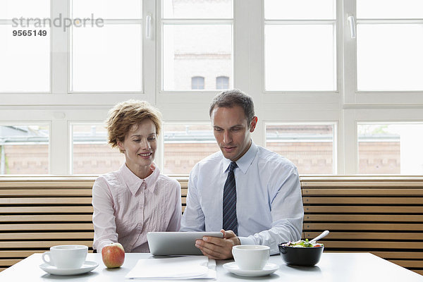 Geschäftskollegen  die ein digitales Tablett während eines Geschäftsessens verwenden