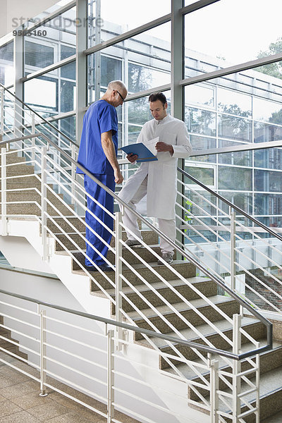 Zwei Mediziner sehen sich eine Karte auf einer Treppe an.